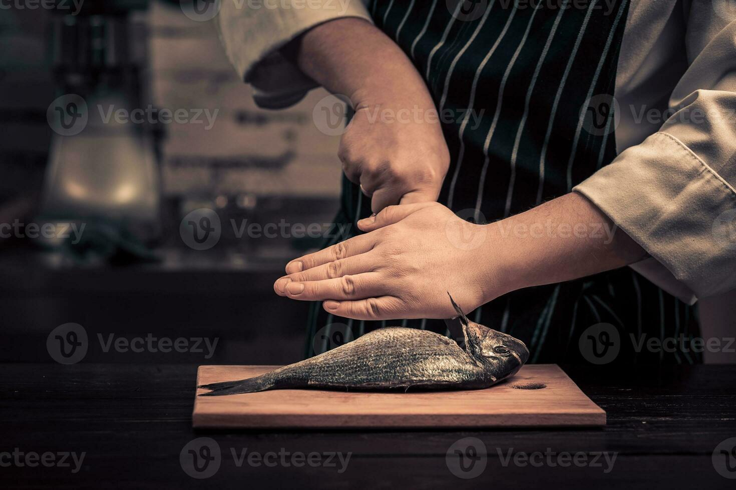 kock skärande de fisk på en styrelse foto