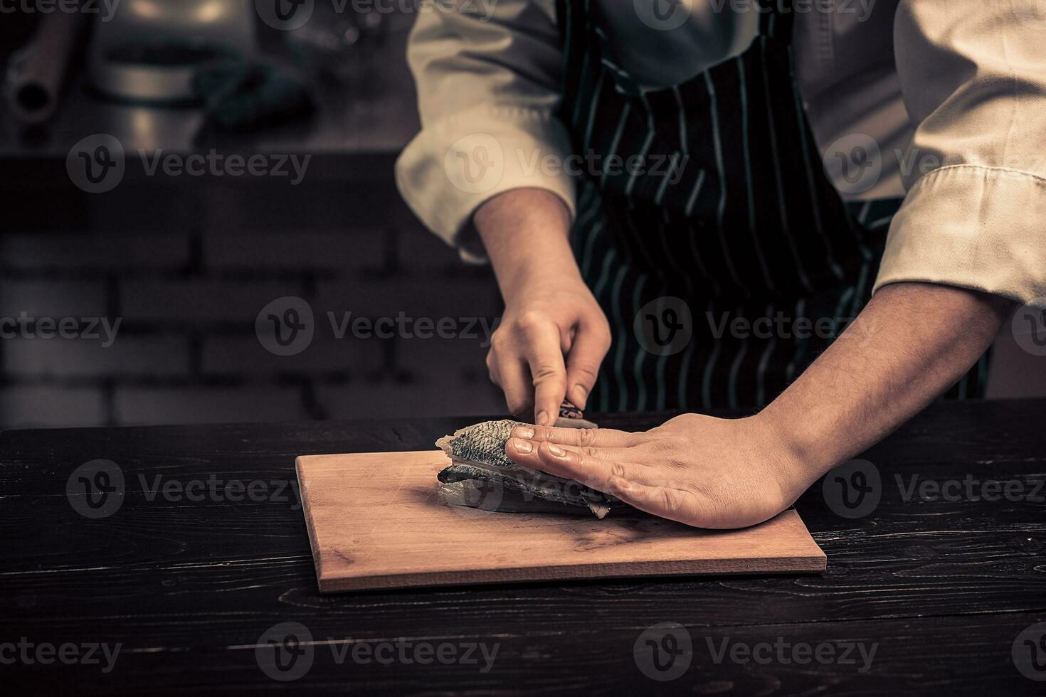 kock skärande de fisk på en styrelse foto