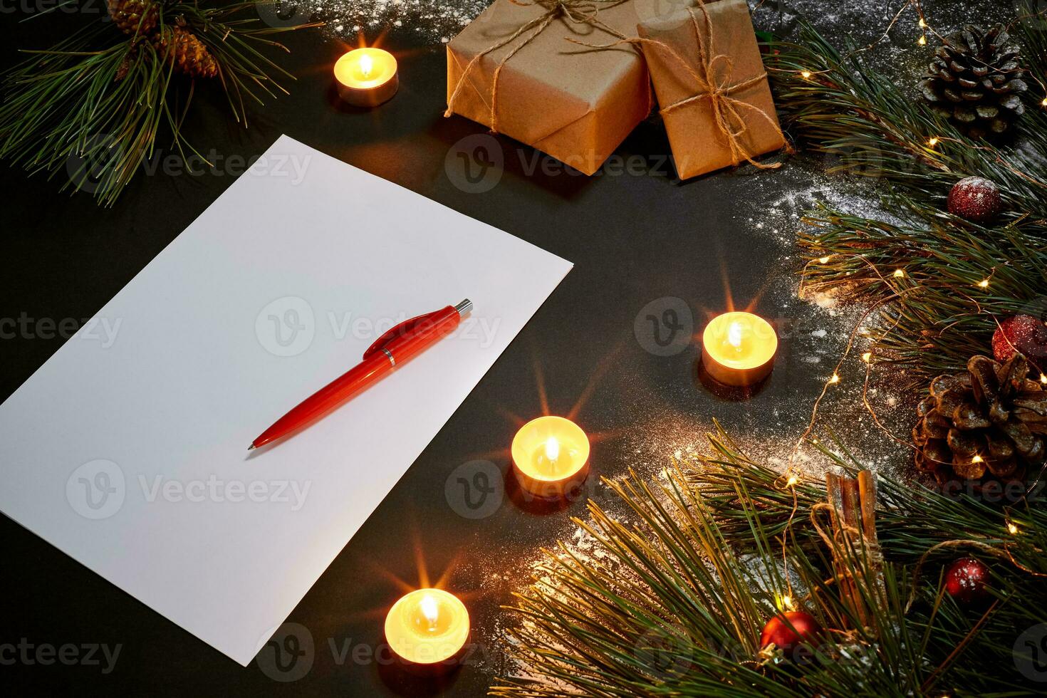 jul leksaker, brinnande ljus och anteckningsbok liggande nära grön gran gren på svart bakgrund topp se. Plats för text foto