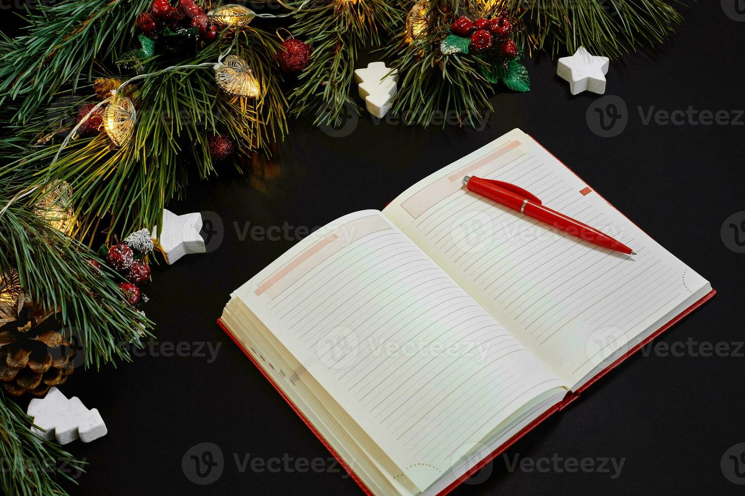 jul bollar och anteckningsbok liggande nära grön gran gren på svart bakgrund topp se. Plats för text foto