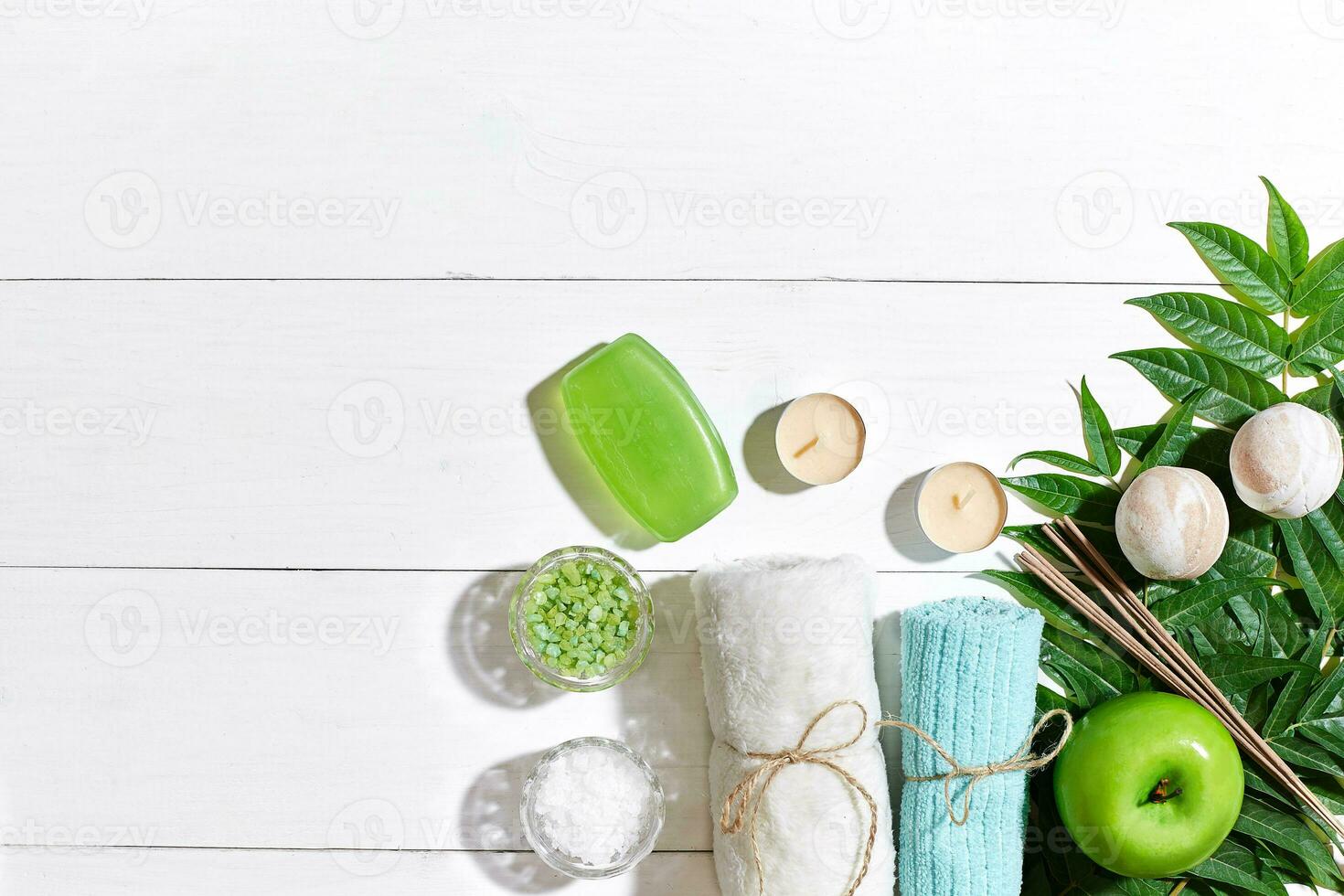 spa uppsättning med handduk och tvål på vit trä- bakgrund med grön löv foto