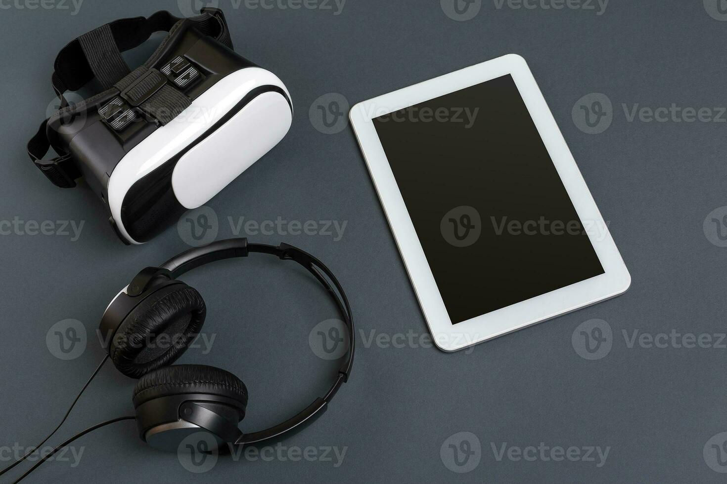 virtuell verklighet glasögon och läsplatta med hörlurar på en grå bakgrund. topp se foto