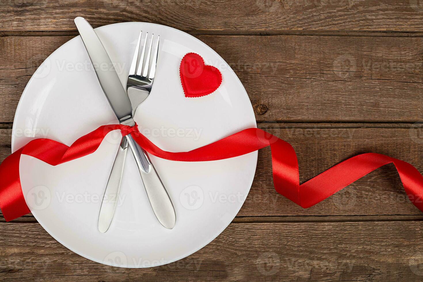 valentines dag tabell miljö med tallrik, gaffel, kniv, röd hjärta och band. bakgrund foto