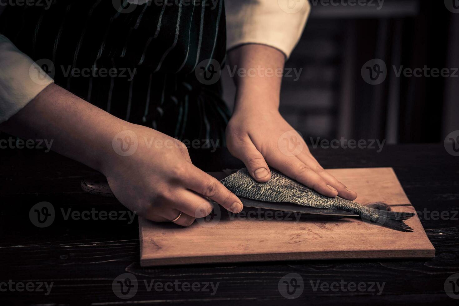 kock skärande de fisk på en styrelse foto