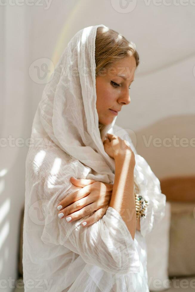 skön ung kvinna med henne huvud täckt. skönhet flicka i hijab. mode orientalisk stil modell i vit modern interiör. foto