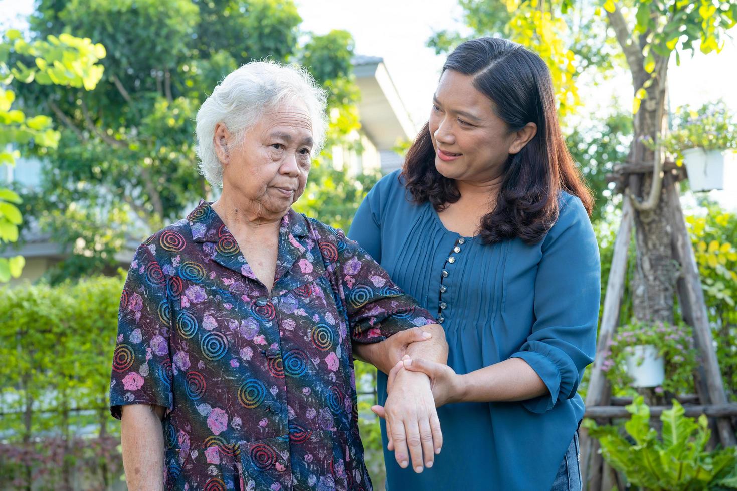 asiatisk äldre kvinna med vårdgivare som går med glad i naturparken foto