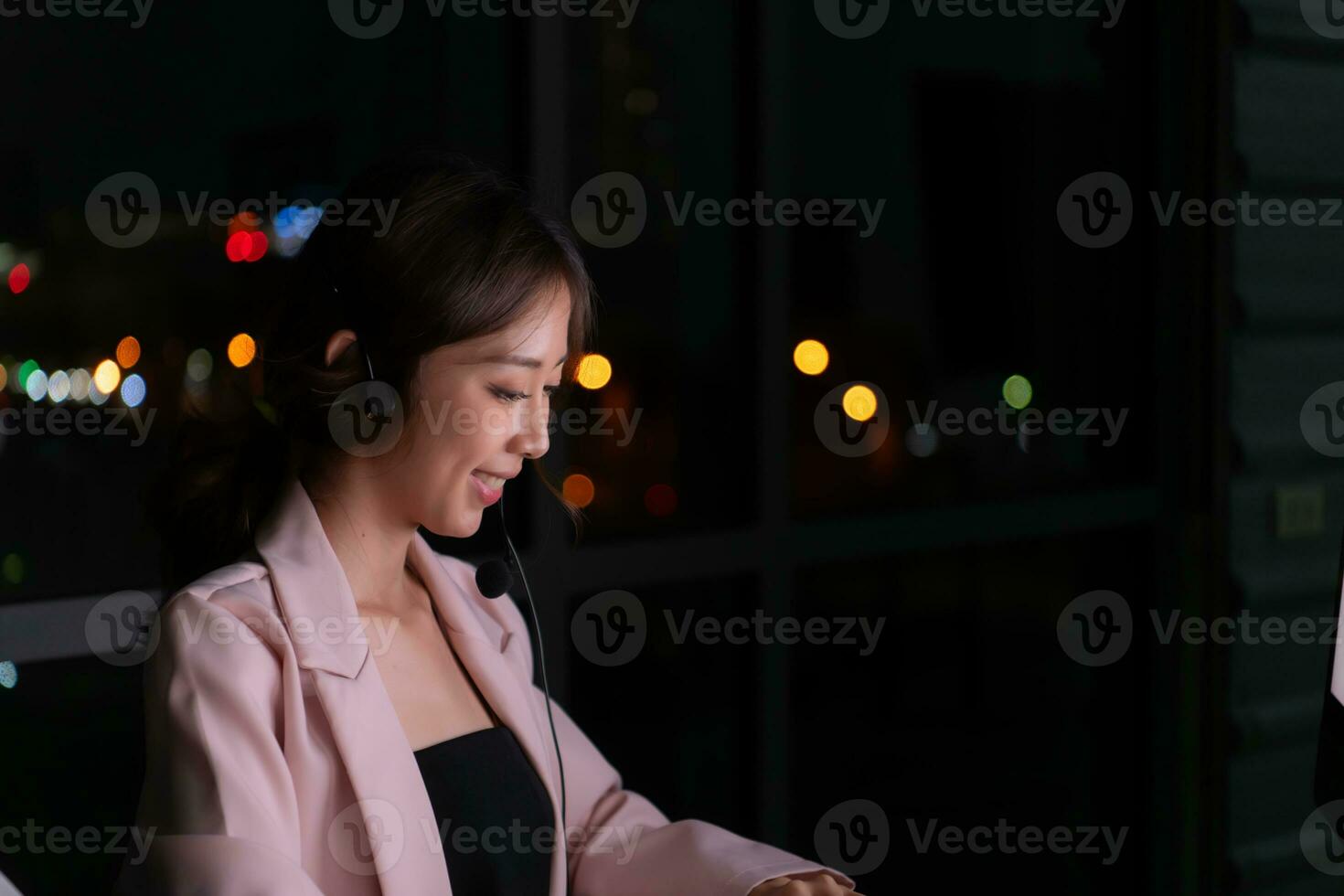 ung asiatisk kvinna mäklare internationell stock handlare bär headsetet arbetssätt aktivt på natt i kontor, begrepp av kund Stöd ombud förse service på telefon. foto