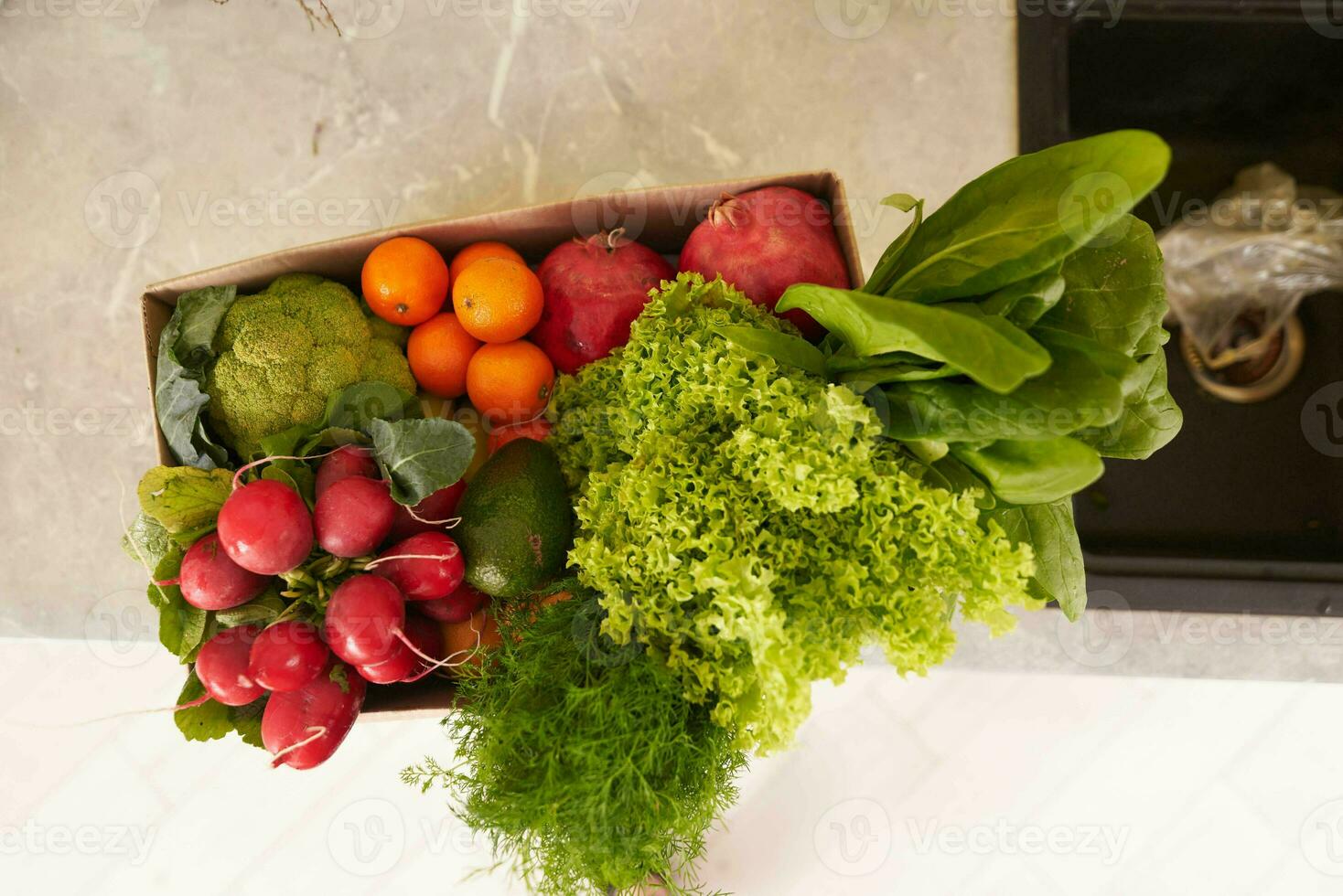 topp se av en återvinningsbar kartong låda med färsk organisk beskära av frukter, grönsaker och grönt på de kök disken foto