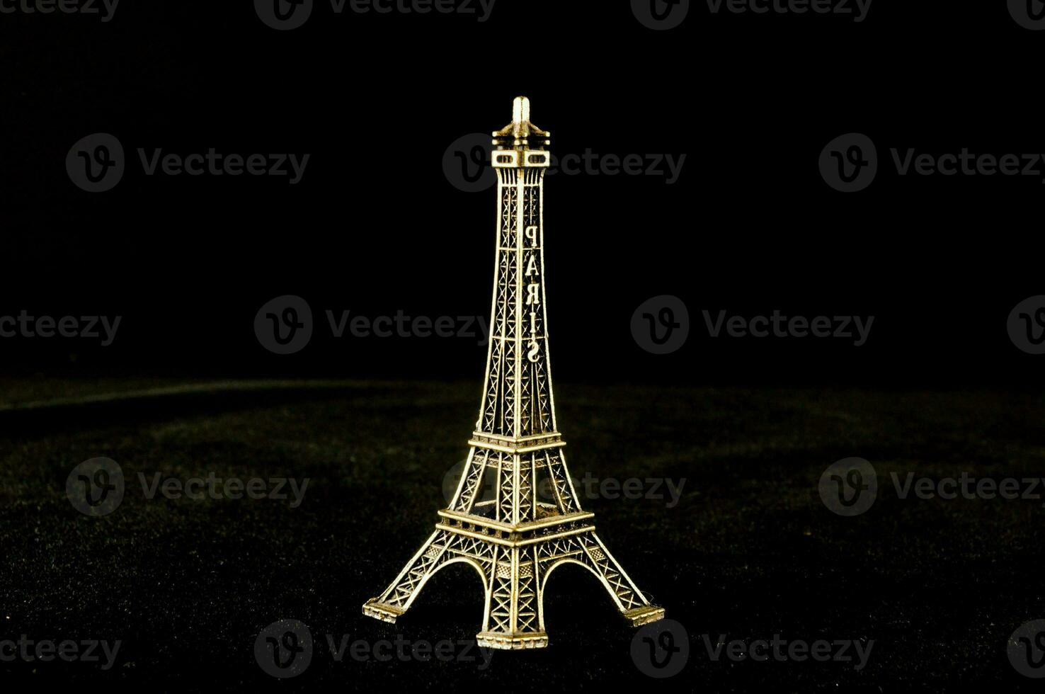 en små guld eiffel torn på en svart bakgrund foto