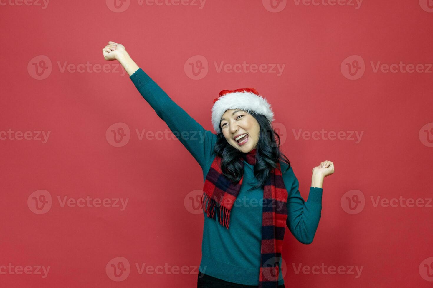 Söt leende asiatisk kvinna i värma jul Tröja och santa hatt på röd bakgrund för säsong firande begrepp foto