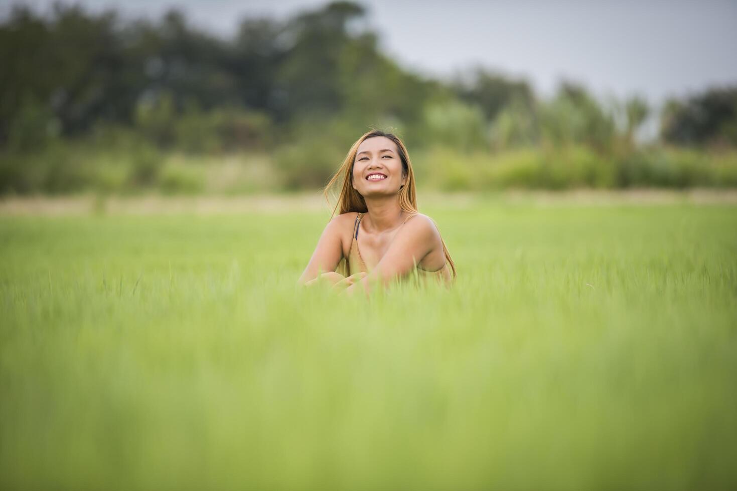 ung kvinna som sitter må bra i gräsfält. foto