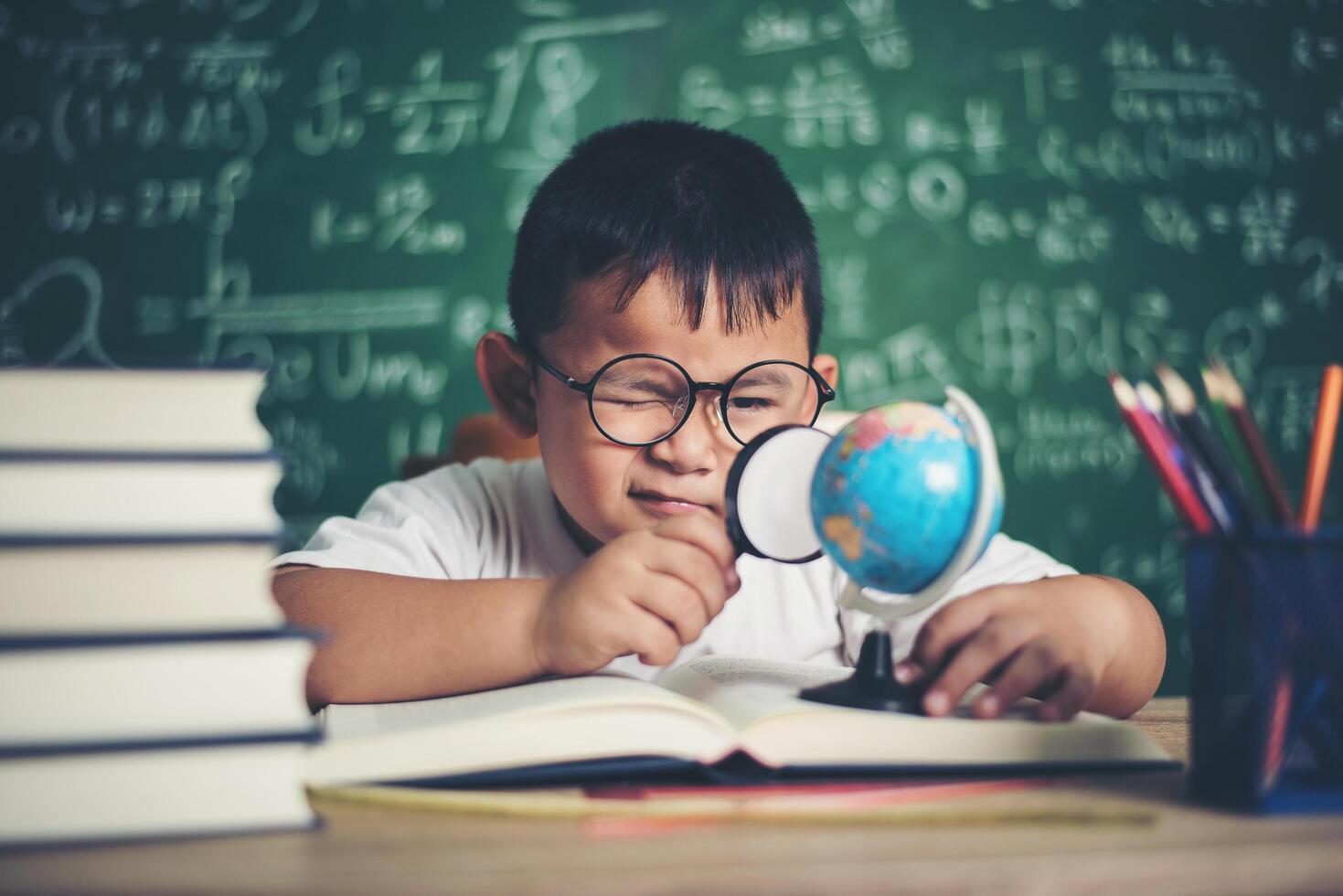 barn som observerar eller studerar pedagogisk klotmodell i klassrummet. foto