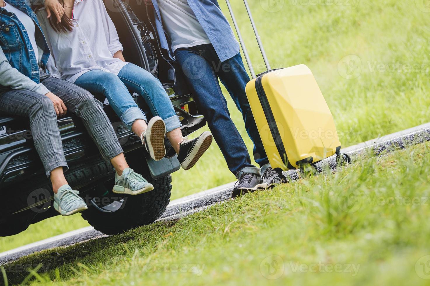 närbild underkroppen av grupp vänner koppla av på suv bil bagageutrymme foto