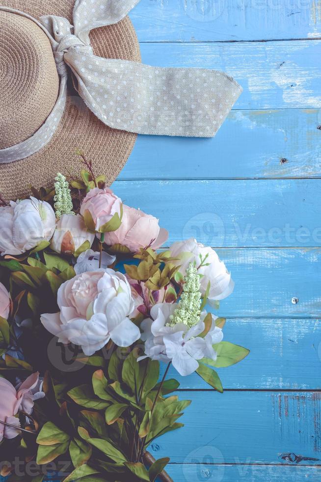 solhatt och blommor på blå träplankbakgrund foto