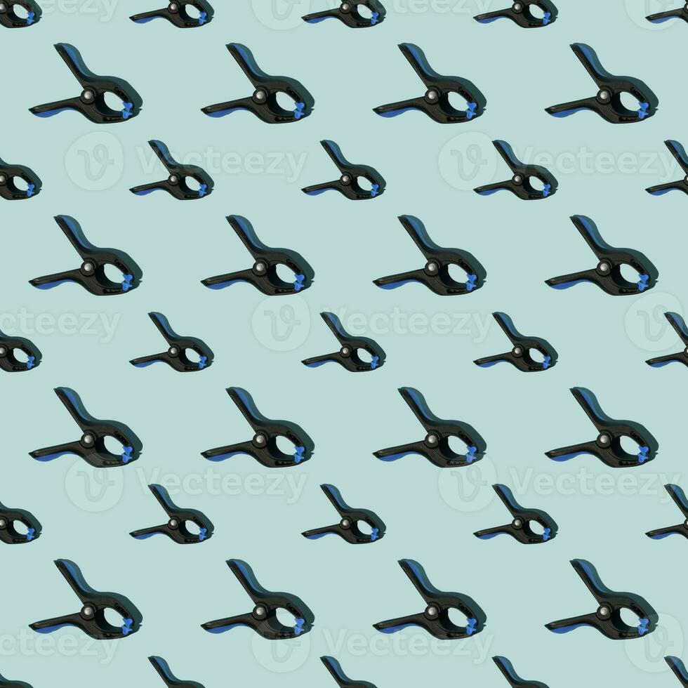 sömlös mönster av svart multipurpose klämmor med blå greppar. blå bakgrund. foto