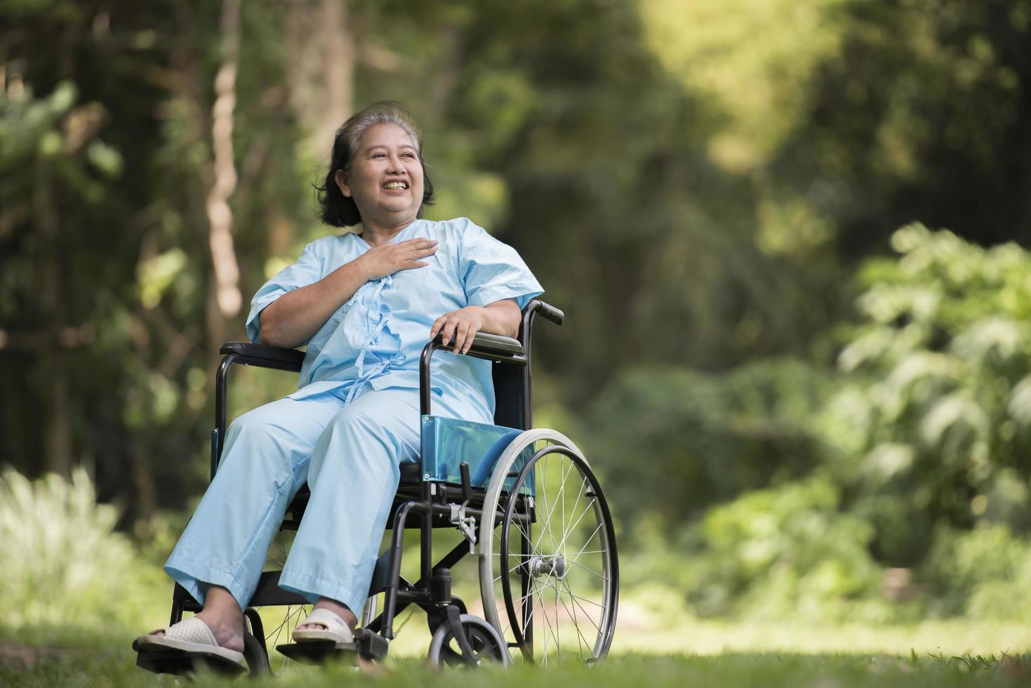 ensam äldre kvinna sitter ledsen på rullstolen i trädgården foto