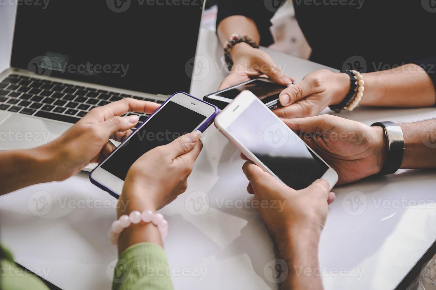 grupp unga hipsters som håller mobiltelefoner i händerna på kontoret foto