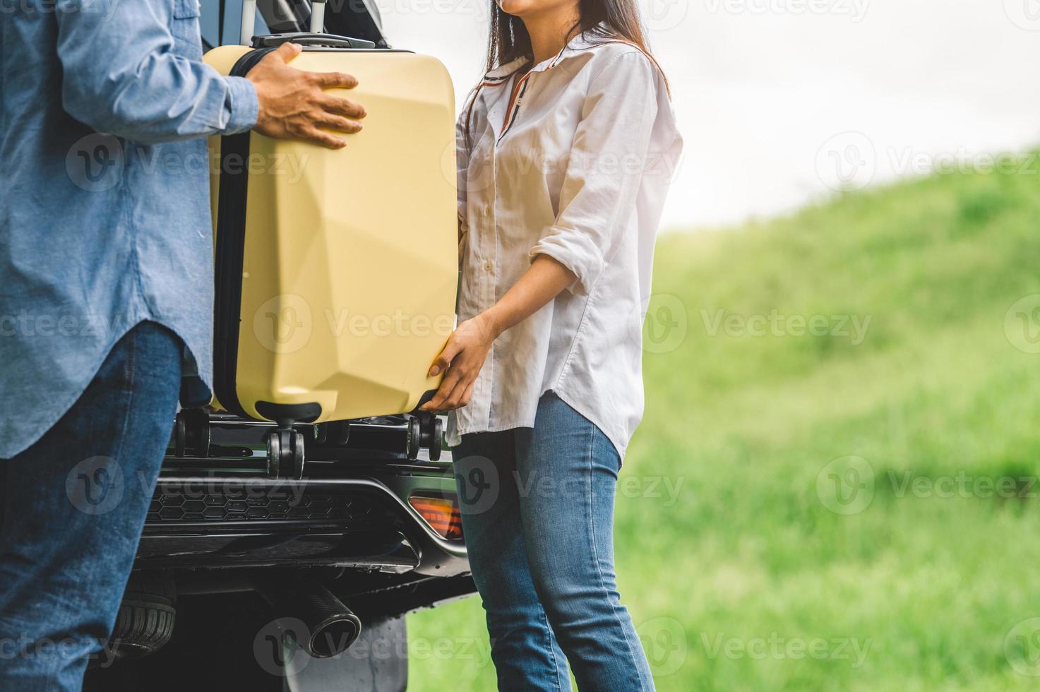 asiatisk man som hjälper kvinnan att lyfta resväska från bilen foto