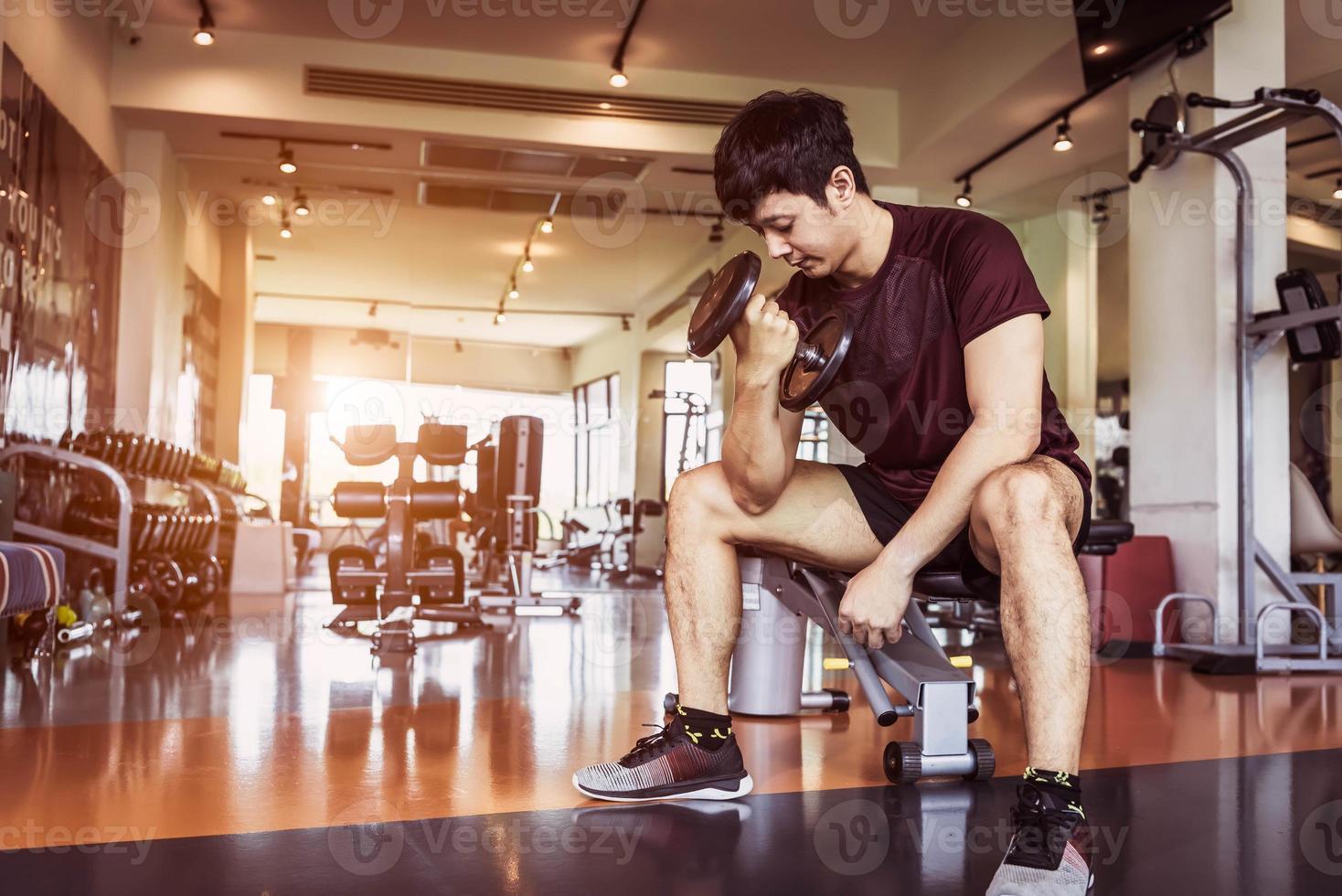 asiatisk sport man lyft hantel på fitness bänk med gym foto