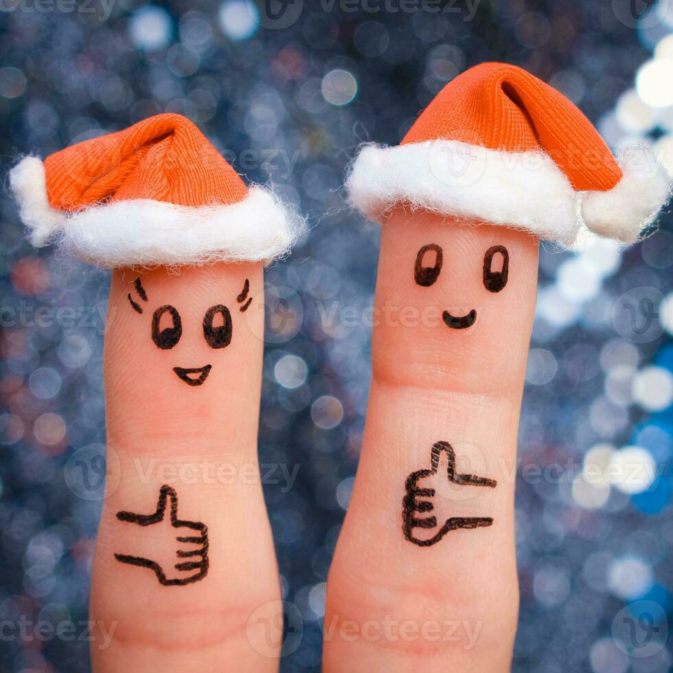 finger konst av par firar jul. begrepp av man och kvinna skrattande i ny år hattar. Lycklig par som visar tummen upp. tonad bild. foto
