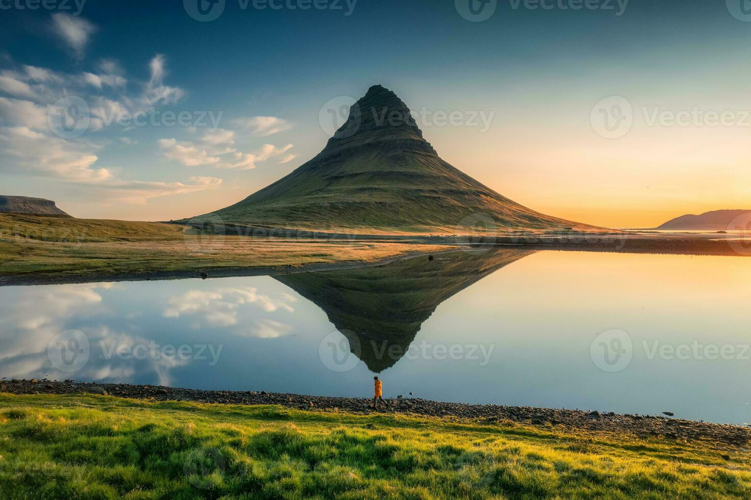vulkanisk Kirkjufell berg med sjö reflexion och resande man stående under soluppgång på island foto