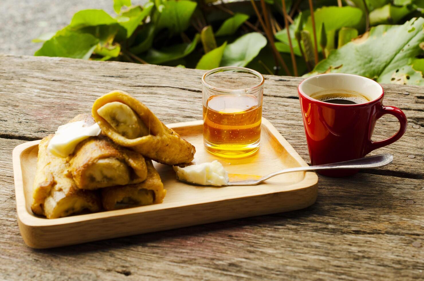 banan fransk toast med honung på träplatta och röd kaffekopp foto