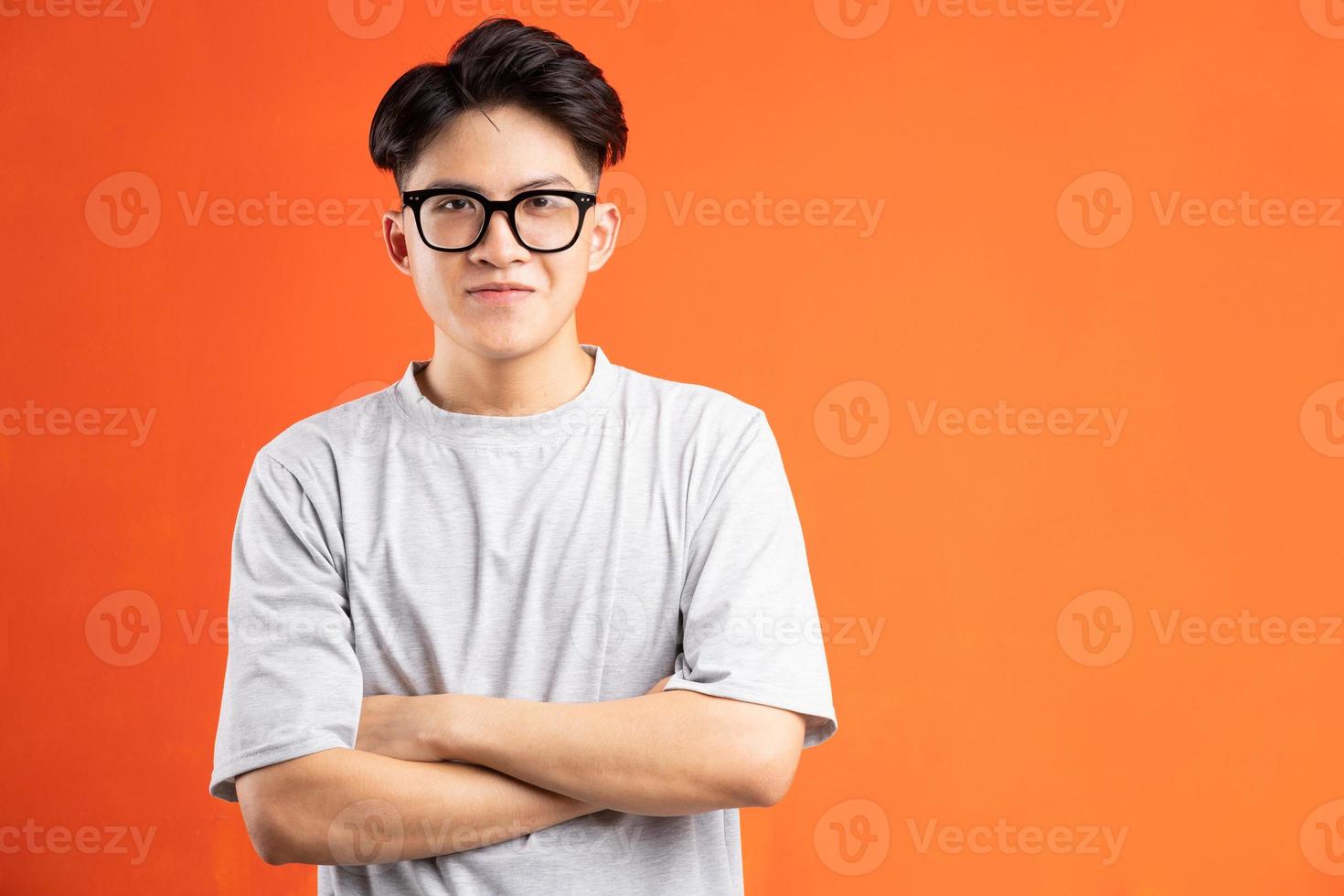 porträtt av den glada leende asiatiska mannen, isolerad på orange bakgrund foto