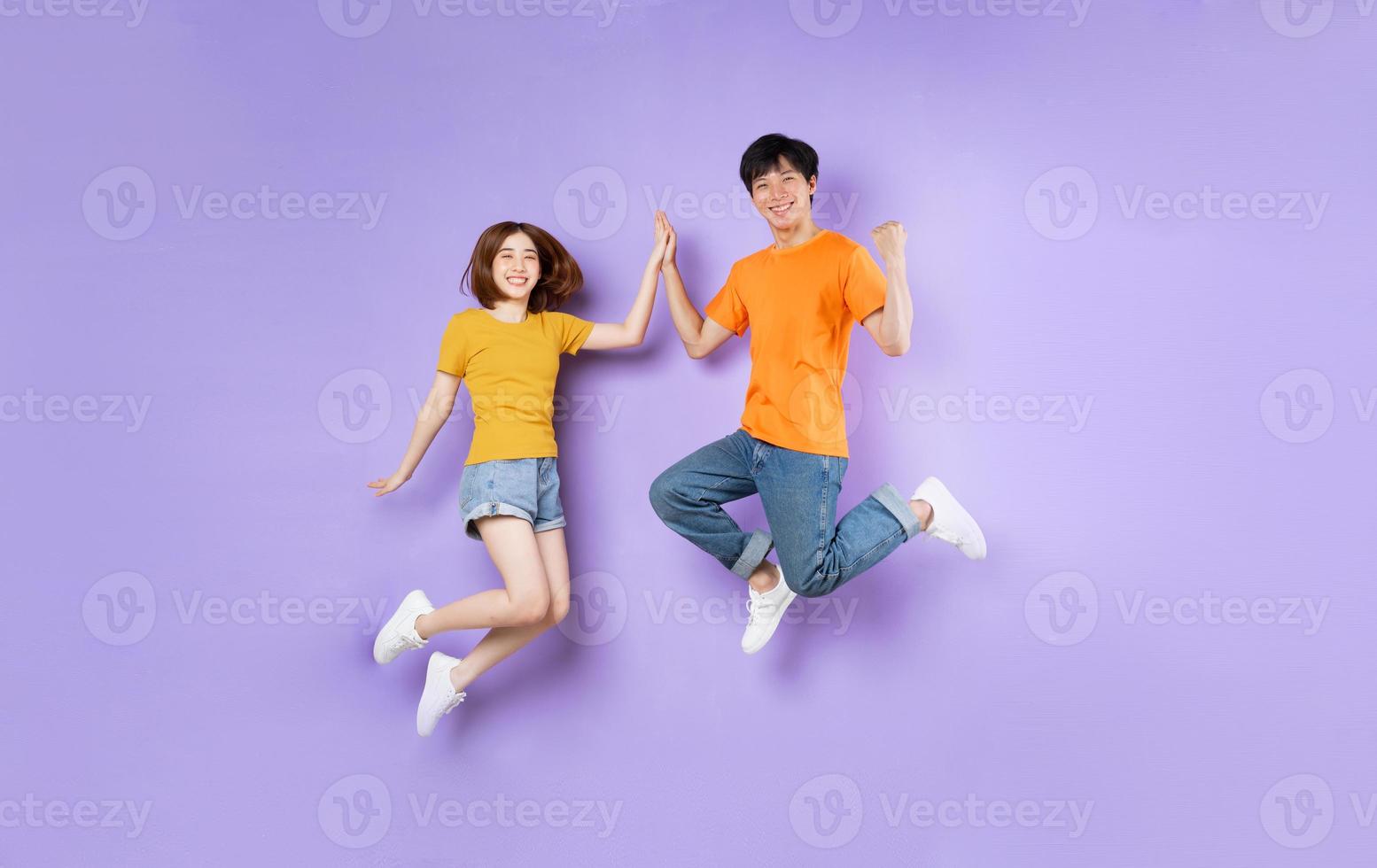 porträtt av ett par som hoppar upp, isolerat på lila bakgrund foto