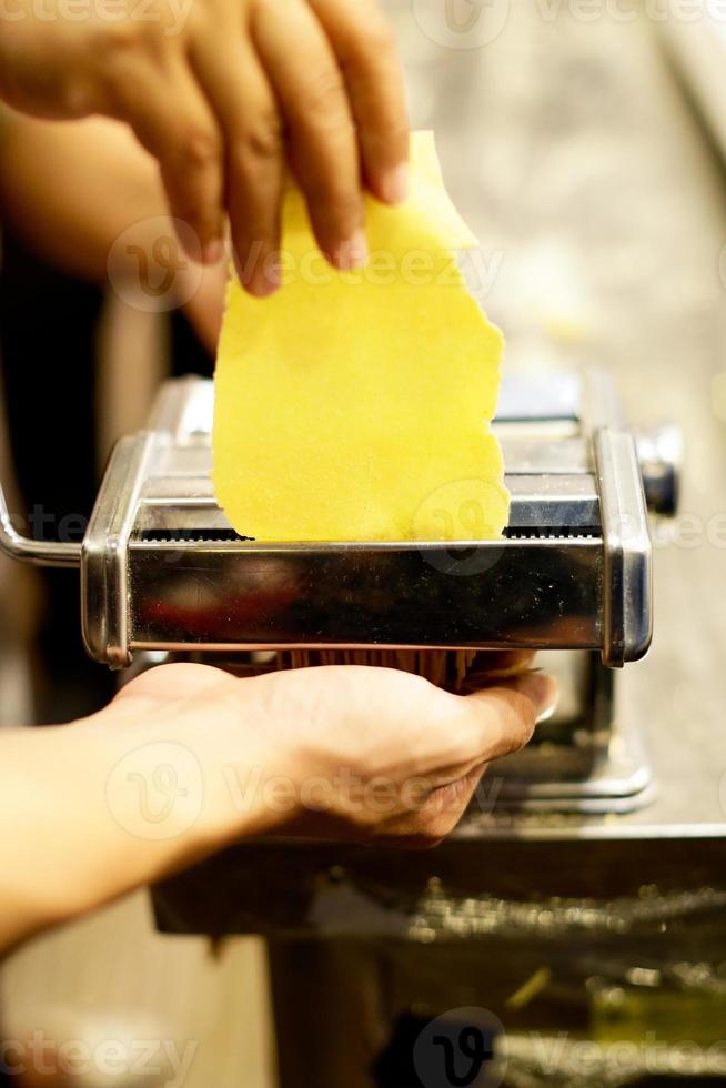 kock som gör pasta med en maskin, hemlagad färsk pasta foto