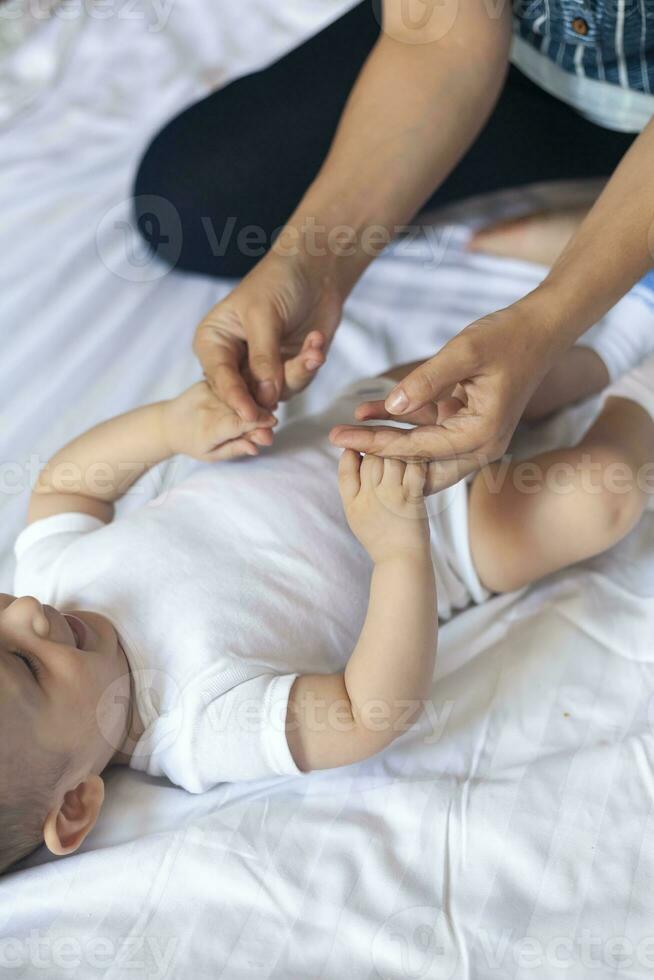 bebis massage. mamma håller på med gymnastik med unge. mamma masse söt bebis pojke. rör på sig bebis ben till hjälp lindra förstoppning. ung mor håller på med övningar och rörelser till stimulera bebis tarmar. foto