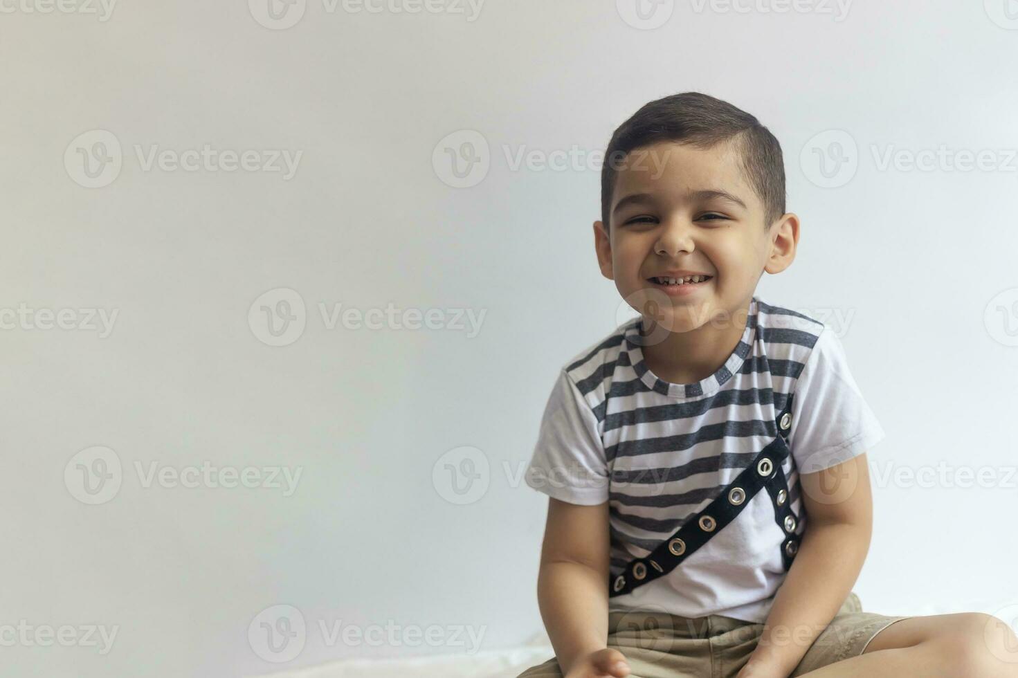 sex år pojke porträtt. oskyldig leende liten pojke på grå bakgrund. liten pojke vrider sig hans ansikte. människor, barndom livsstil begrepp. foto
