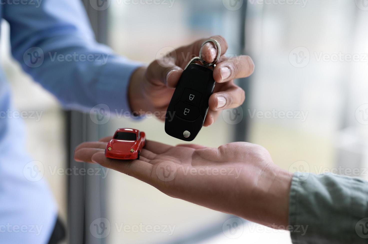 närbild av byte av bilnycklar och modellbilar. foto
