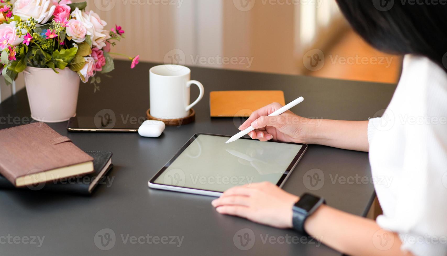 unga kvinnor skriver på modern surfplatta med en digital penna på ett svart skrivbord. foto