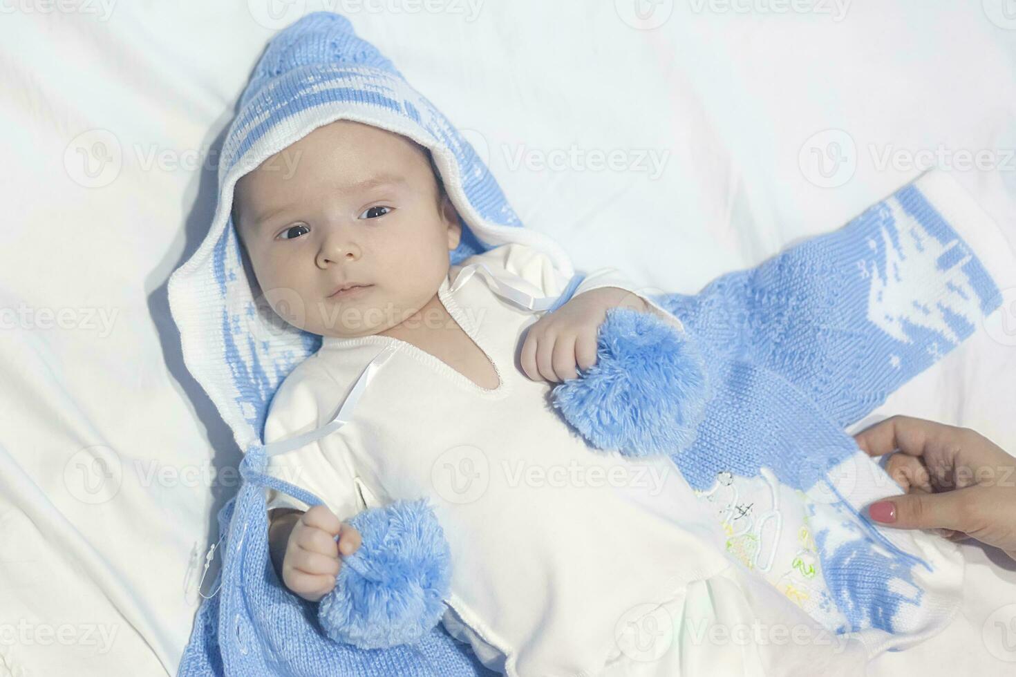 skön nyfödd bebis på vit säng med vit bakgrund bär blå hatt eller trasa foto