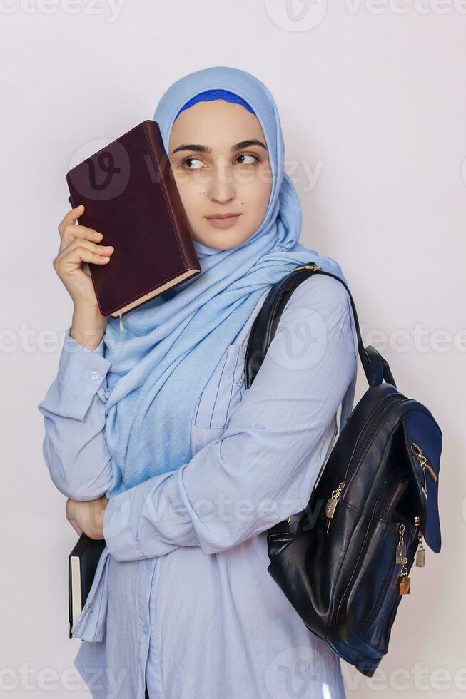 modern muslim studerande flicka i hijab. ung Mellanöstern högskola studerande med ryggsäck innehav böcker och anteckningsblock. isolerat på vit bakgrund. porträtt av ung arab kvinna studerande foto