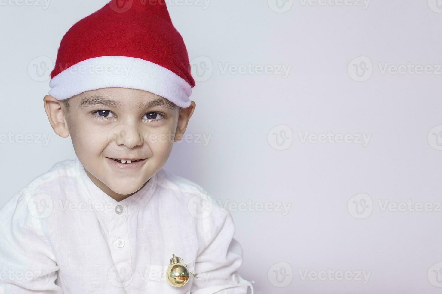 Lycklig liten jul pojke. fira jul. 6-7 år gammal unge med santa hatt. foto