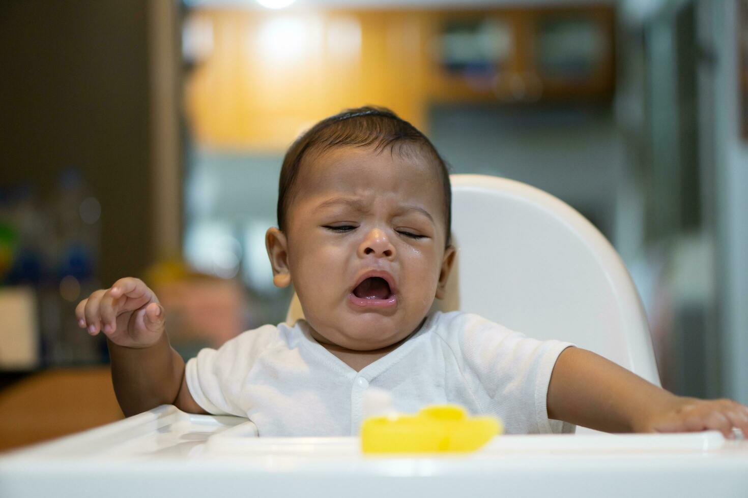 ett asiatisk bebis gråt på dining stol foto