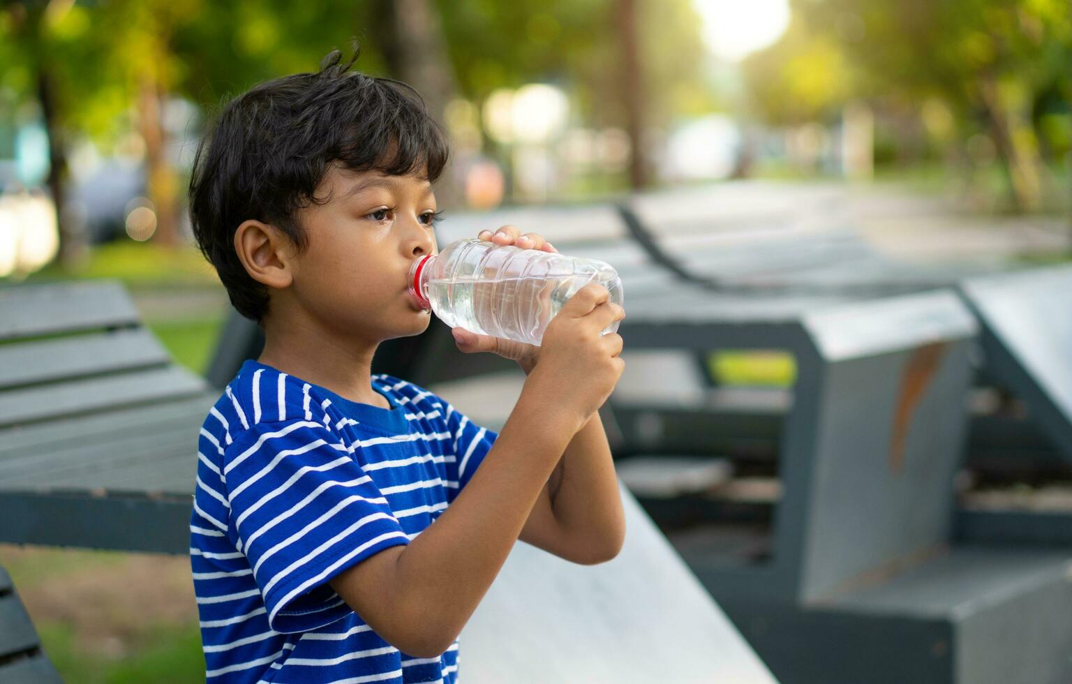 unge dricka vatten från en transparent plast flaska. foto