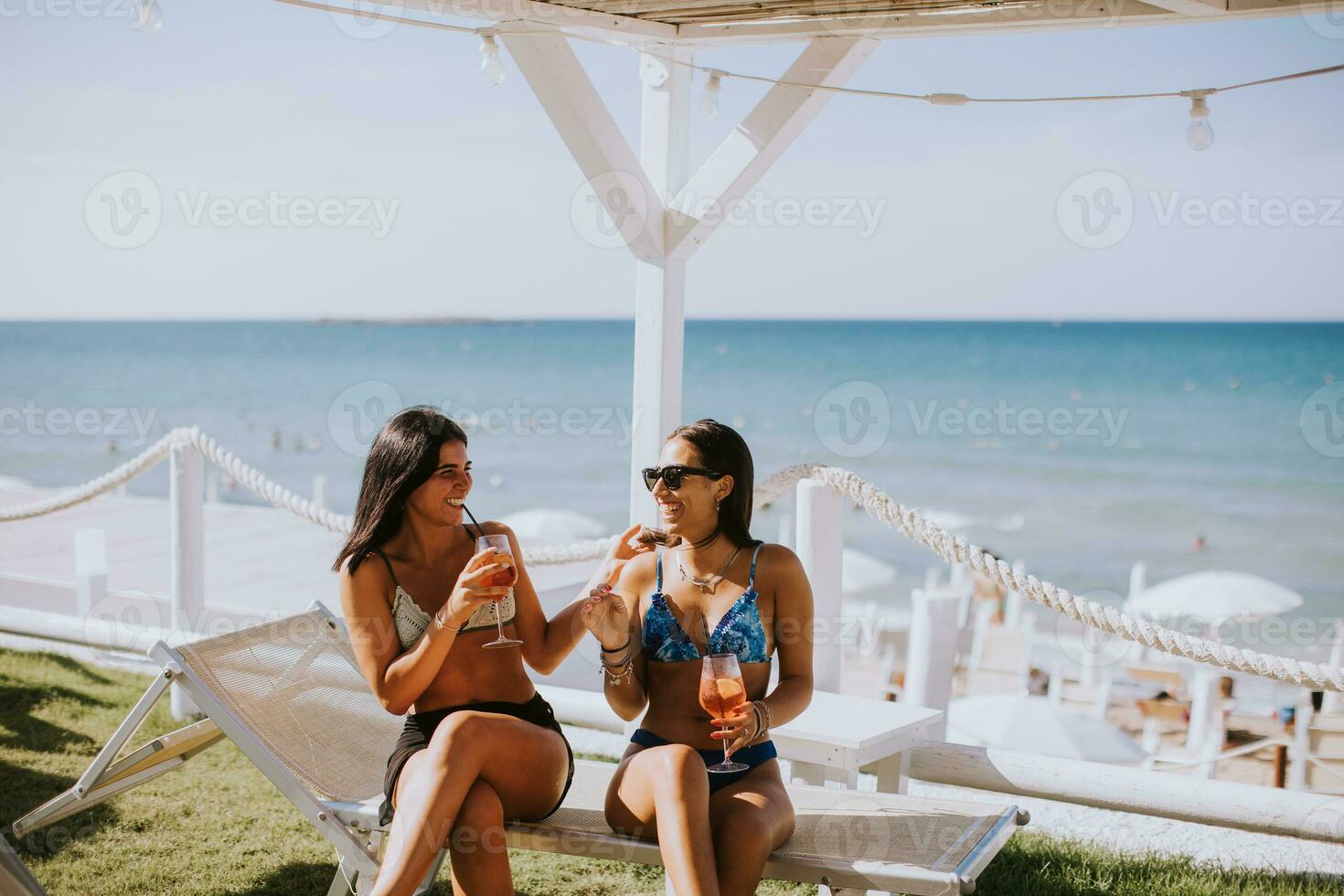 leende ung kvinnor i bikini njuter semester på de strand foto