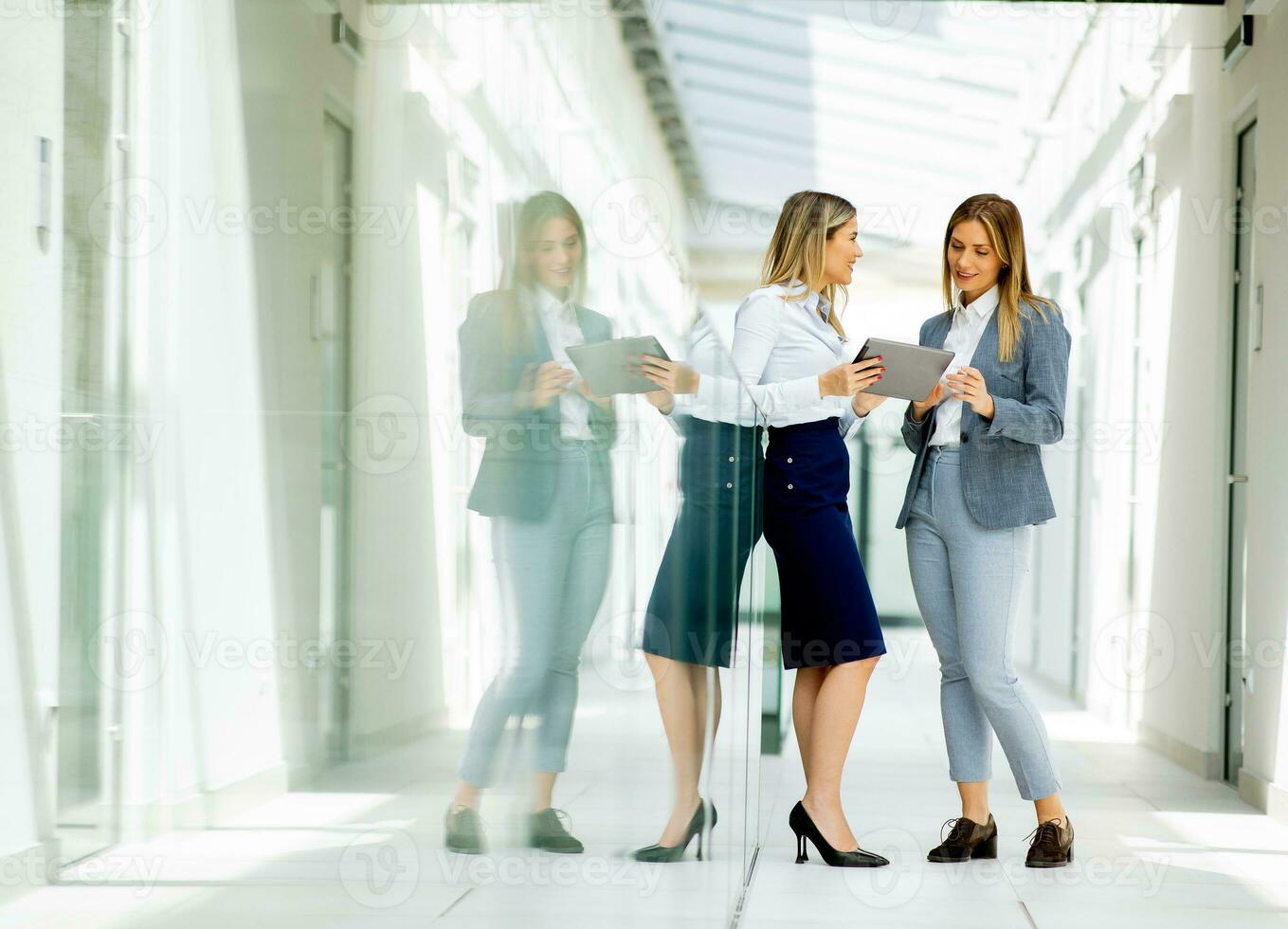 två ung företag kvinnor med digital läsplatta i de kontor hall foto