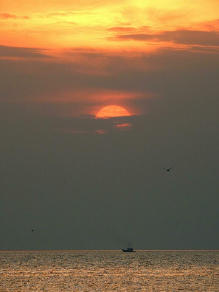 solnedgång och ensam båt på thailand hav foto