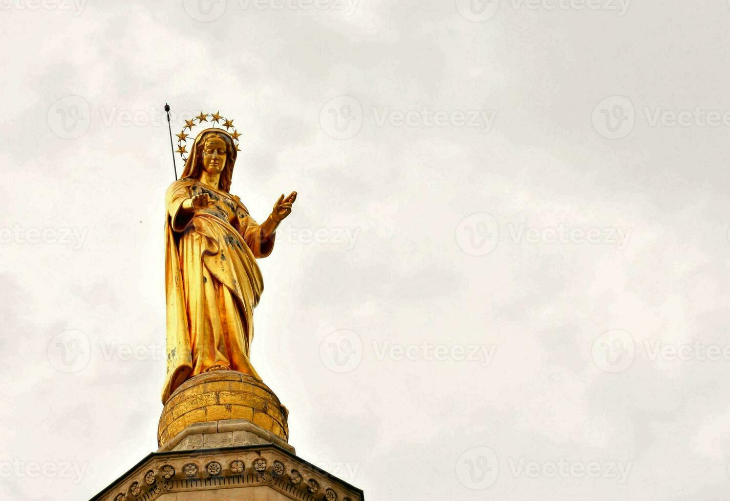 en guld staty av mary på topp av en byggnad foto