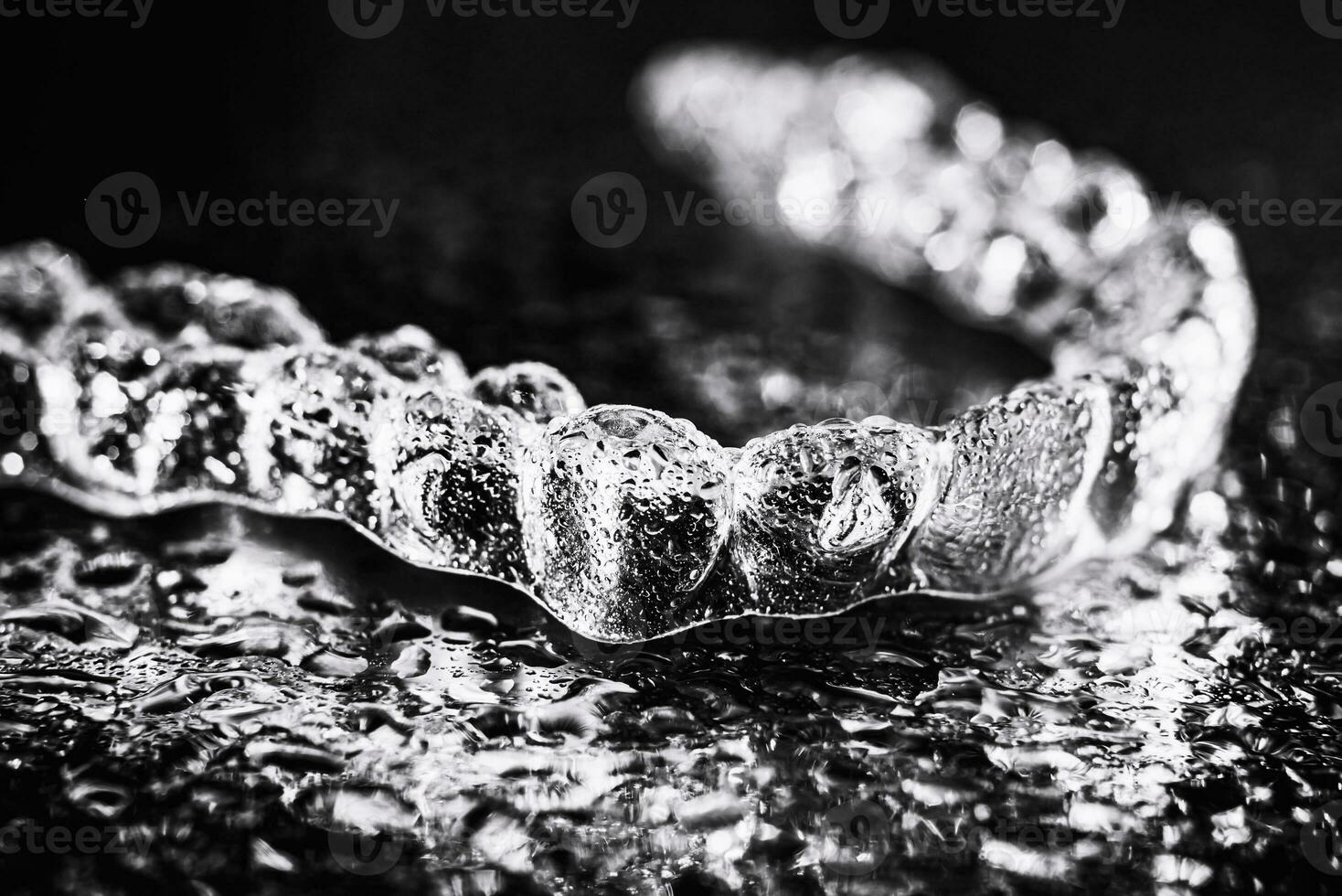 transparent aligners, tand hållare lögn på en spegel med vatten droppar på en svart bakgrund foto