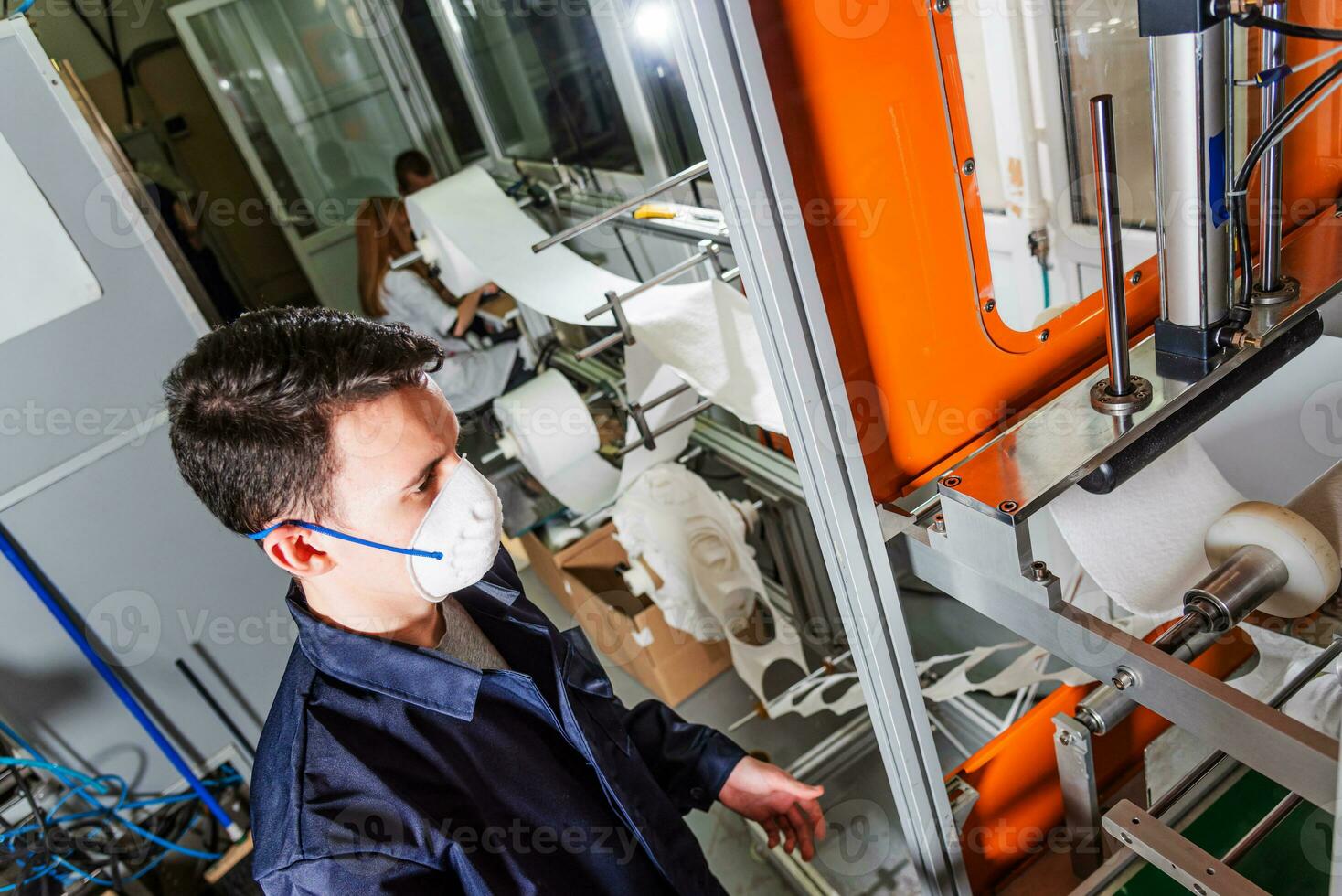 en arbetstagare står på de maskin i en fabrik för de tillverkning av medicinsk masker med nanofiber. coronovirus och covid-19 skydd foto