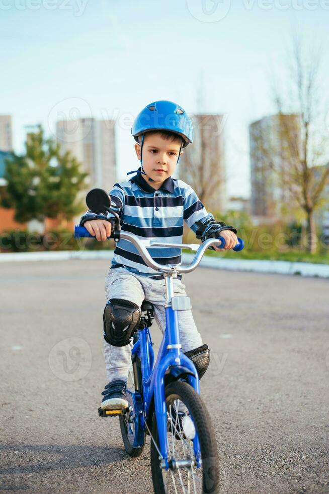 en barn i en hjälm och skydd i en cykel rida på natur i de vår foto