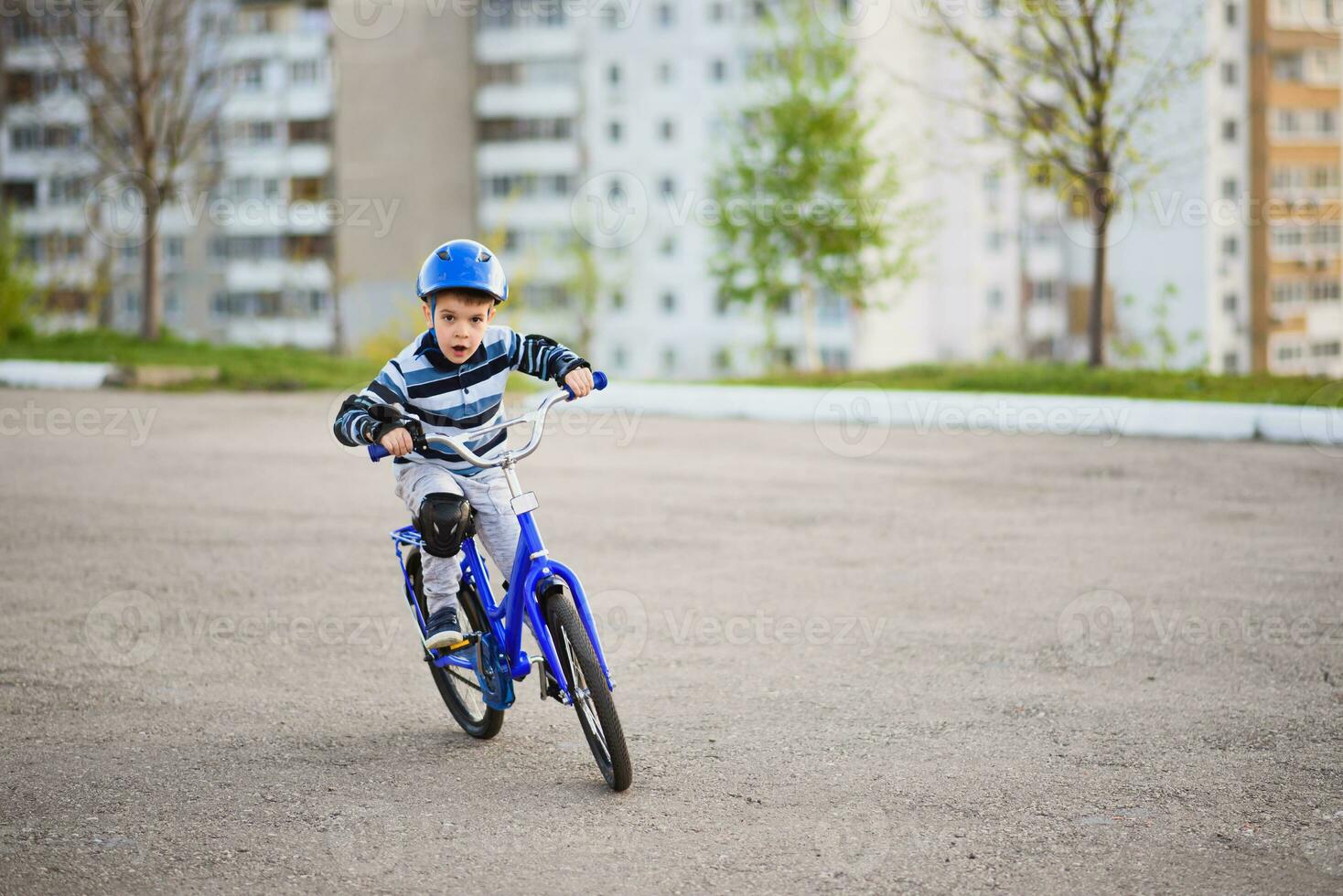 en barn i en hjälm och skydd i en cykel rida på natur i de vår foto