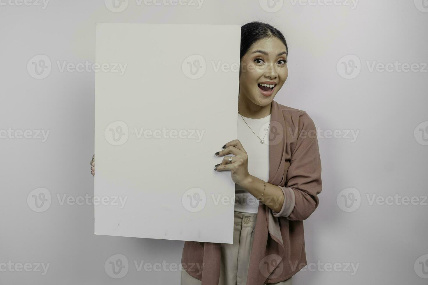 leende ung asiatisk kvinna anställd innehav och som visar tömma tom styrelse, isolerat förbi vit bakgrund foto