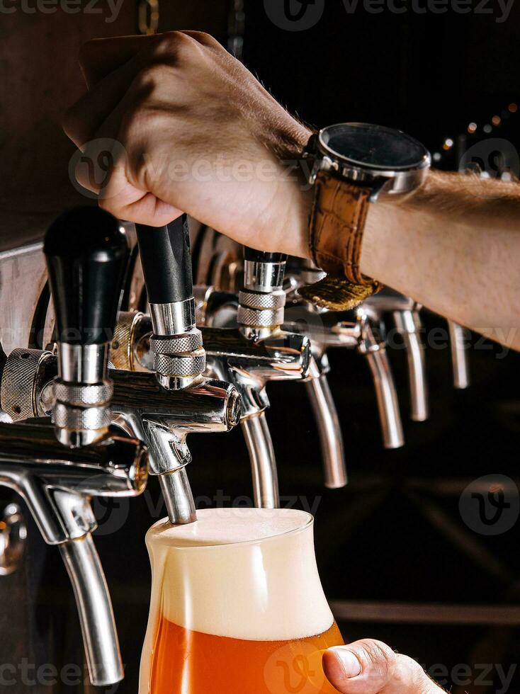 bartender häller färsk öl in i glas i pub foto