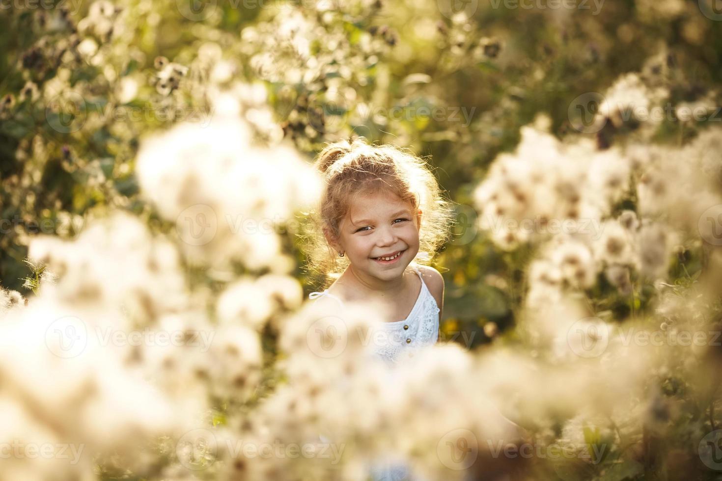 glad glad liten flicka bland vildblommor foto
