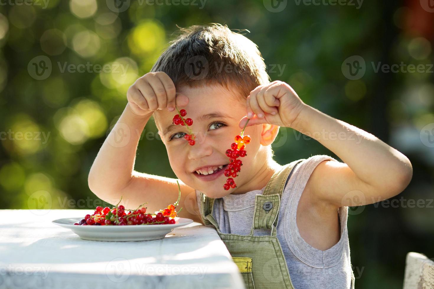 glad pojke som håller en röd vinbär foto